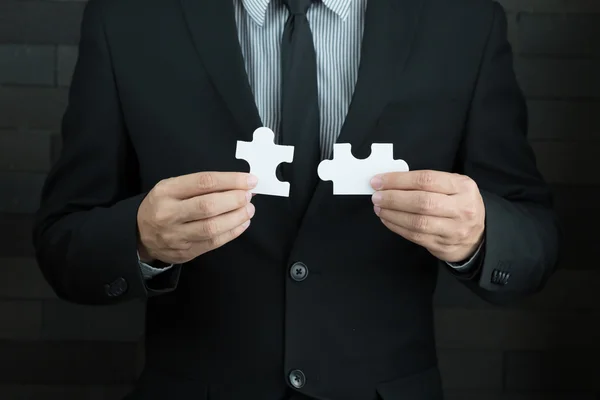 Empresarios sosteniendo dos rompecabezas para conectar — Foto de Stock