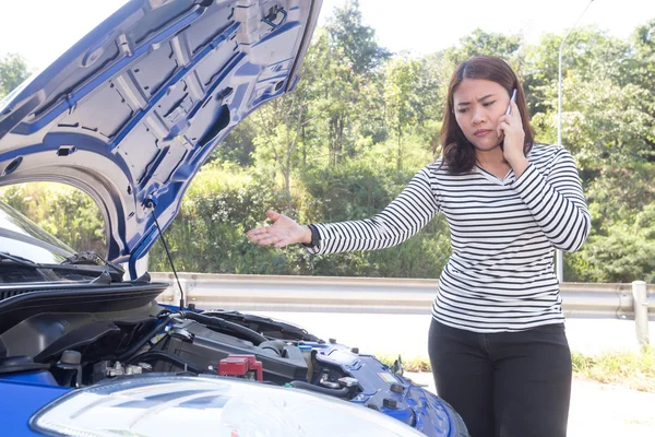 Asian women calling for assistance after breaking down car engin