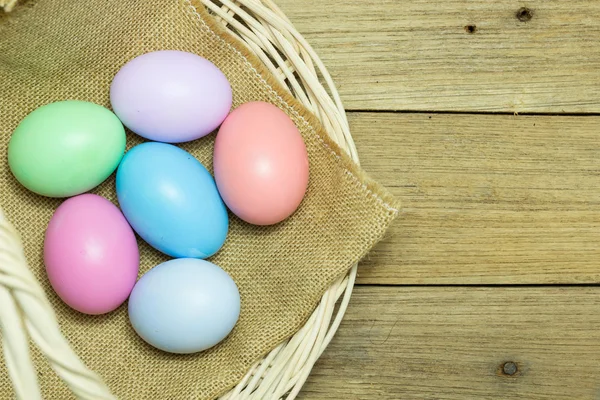 Uova di Pasqua nel cestino su fondo legno — Foto Stock