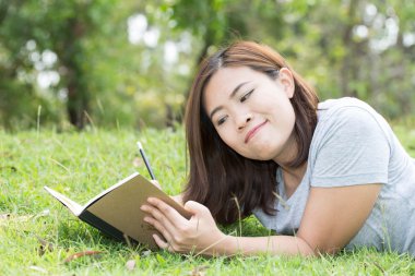 Asyalı kadın bahçede bir kitap yazma