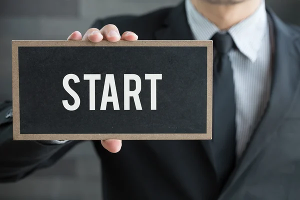 Start, word on blackboard and hold by businessman — Stock Photo, Image