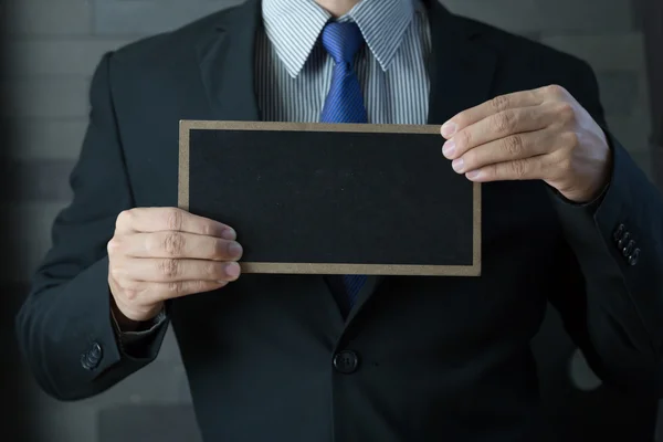 Hand of businessman showing black board — Stock Photo, Image