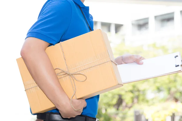 Entrega hombre sosteniendo una caja de paquete y papel blanco en el portapapeles — Foto de Stock