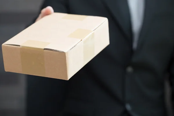 Businessman in suit giving brown box to someone