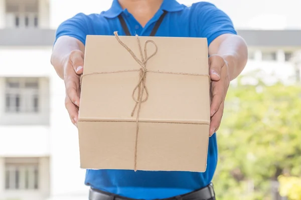 El repartidor sostiene una caja de paquetes. Concepto de servicio de entrega — Foto de Stock