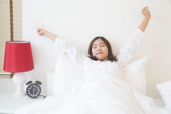 Jovem mulher asiática esticando na cama de manhã — Fotografia de Stock