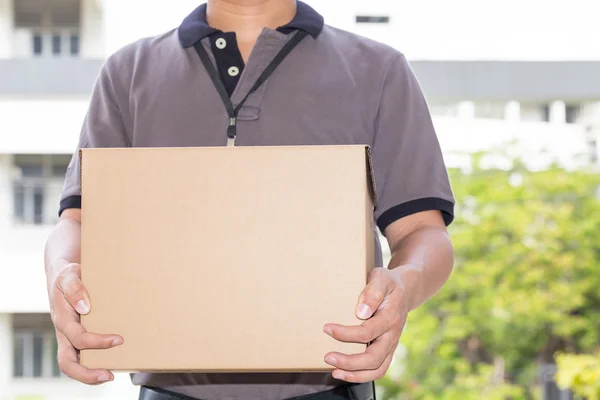 El repartidor sostiene una caja de paquetes. Concepto de servicio de entrega — Foto de Stock