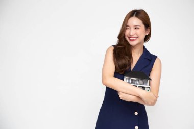 Genç Asyalı kadın gülümseyen ve sarılan rüya ev modeli beyaz arka plan, gayrimenkul ve ev sigortası kavramına izole edilmiş.