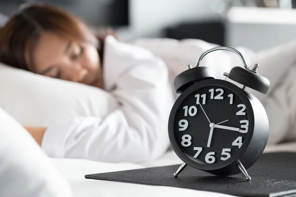 Aziatische vrouw slapen op bed en wake up met wekker — Stockfoto