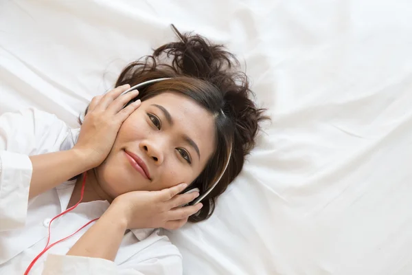 Joven mujer asiática disfrutando de la música en la cama en casa —  Fotos de Stock