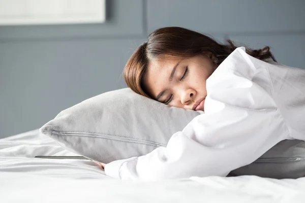 Азиатка спит на кровати — стоковое фото