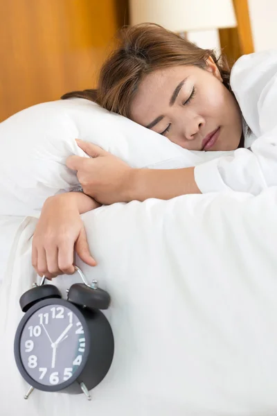 Asiatin schläft auf Bett und wacht mit Wecker auf — Stockfoto