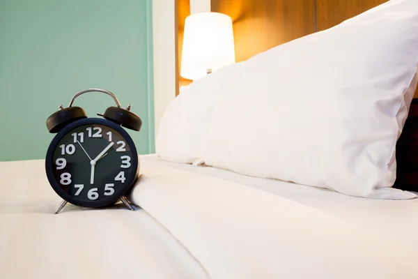 Black alarm clock and bed — Stock Photo, Image