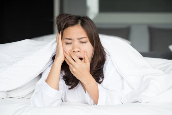 Sleepy asian woman yawning in bed at home — Stock Photo, Image