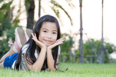 Asyalı küçük kız parkta yalan