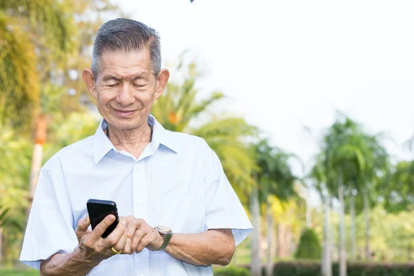 Asiático senior hombre leyendo mensaje en el teléfono inteligente — Foto de Stock