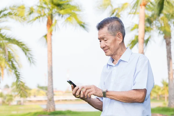 Asiático senior hombre leyendo mensaje en el teléfono inteligente — Foto de Stock