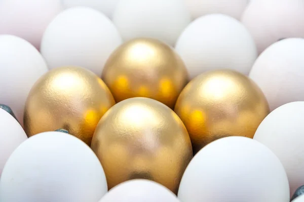 Золоті яйця серед білих яєць — стокове фото