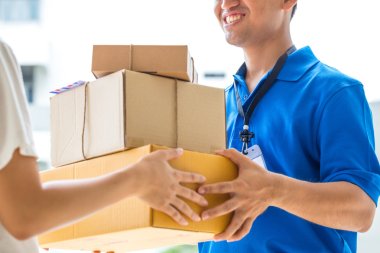 Woman accepting a delivery of cardboard boxes from deliveryman clipart