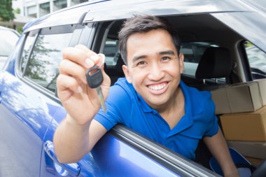 Gülümseyen ve arabanın anahtarını gösteren Asyalı adam sürücü