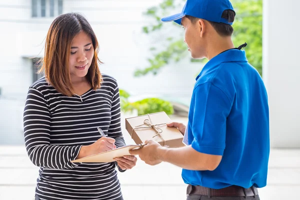 Mulher asiática que assina o recibo do pacote entregue — Fotografia de Stock