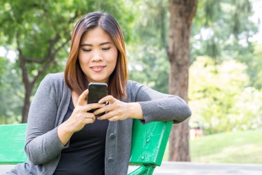 Asyalı kadın parkta Smartphone kullanarak