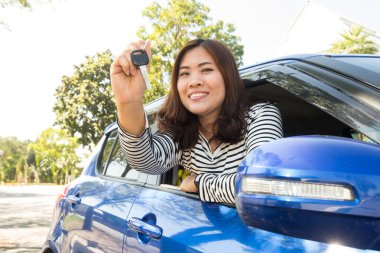 Yeni araba anahtarları gösteren gülümseyen Asya araba sürücüsü kadın