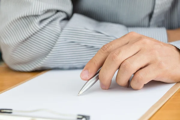 Libro blanco de firma de mano humana sobre mesa de madera Imágenes de stock libres de derechos