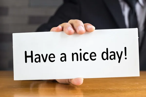 Ha en trevlig dag, meddelande på vitt kort och håll av affärsmannen — Stockfoto