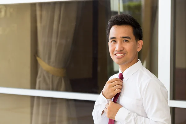 Asian businessman straightening his tie