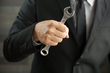 İngiliz anahtarını elinde tutan işadamı