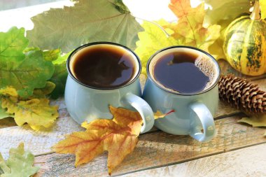 Birkaç fincan sıcak kahve, balkabağı, arka planda yapraklar, ev konforu, Şükran Günü, sonbahar sezonu. 