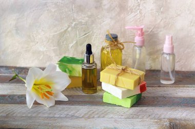 Sabun, antiseptik sprey ve aromatik yağ şişeleri, ahşap bir masada beyaz zambak çiçeği, doğal kozmetik ürünleri, ev bakım ürünleri, sağlıklı yaşam tarzı, temizlik.
