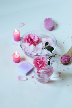 Taze pembe güller, su, taç yaprakları, arka planda mumlar, vücut bakım ürünleri, doğal ev ürünleri, sağlıklı yaşam tarzı.