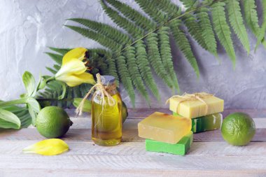 Sabun, limon, aromatik yağ ve ahşap bir masada taze çiçekler, doğal ev kozmetik ürünleri, sağlıklı yaşam tarzı.