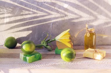 Sabun, limon, aromatik yağ ve ahşap bir masada taze çiçekler, doğal ev kozmetik ürünleri, sağlıklı yaşam tarzı.