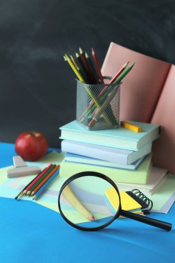 Okula, kitap yığınına, büyüteç ve kırtasiye malzemelerine. 