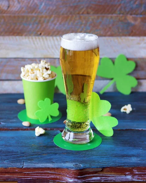 Beer, popcorn in paper cups in the shape of St. Patrick\'s hat, shamrock on a wooden table, party, congratulation, postcard