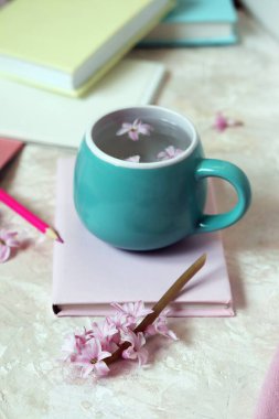 Su ve taze sümbül çiçekleri, kitaplar, not defterleri, hafif arka planda yün pembe süveter, evde romantik bir kutlama, aşk duygusu.