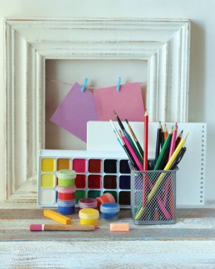 Tablolar, renkli kalemler ve ahşap bir masadaki çerçevenin arka planında boş defterler, öğrenme konsepti, çizim dersi, okula dönüş.