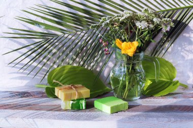 Cam sürahide bir buket şifalı ot, ahşap bir masada sabun, doğal kozmetik ürünler, ev bakım ürünleri, sağlıklı yaşam tarzı, temizlik. 