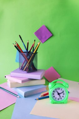 Kitaplar, çalar saat, masadaki kırtasiye malzemesi, eğitim konsepti, okula dönüş.