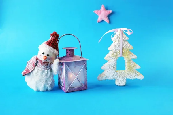 头戴圣诞礼帽的玩具雪人 蓝色明亮背景上点着蜡烛的灯笼 圣诞快乐的理念 恭喜你 明信片 — 图库照片