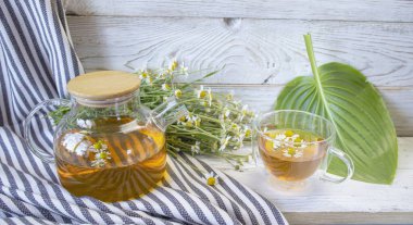 Çaydanlıkta taze papatya çayı ve çiçekli fincan. Doğal malzemeli rahatlatıcı papatya çayı..