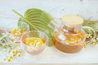 Çaydanlıkta taze papatya çayı ve çiçekli fincan. Doğal malzemeli rahatlatıcı papatya çayı.. 