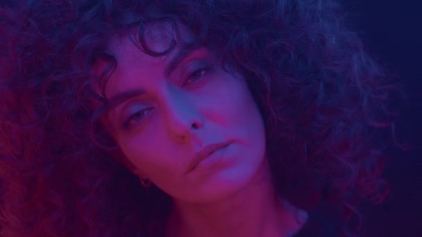 Retrato facial calmo de mulher séria posando em luz de néon, penteado afro encaracolado — Vídeo de Stock
