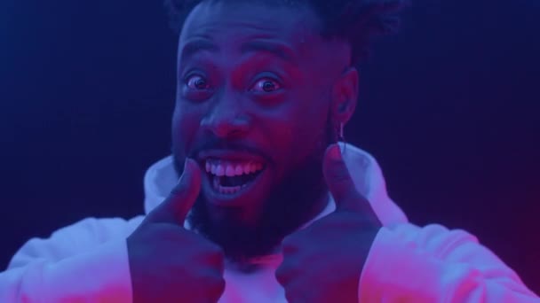Portret twarzy uśmiechniętego, szczęśliwego, afrykańskiego mężczyzny, zabawne emocje w neonowym świetle — Wideo stockowe