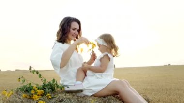 Mutlu anne tarlada kızını kucaklıyor, aile sevgisini. Anne, küçük kızı kucaklıyor.