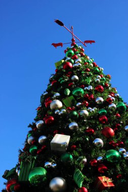 Toplar ve hediyeler şeklinde oyuncaklarla süslenmiş Noel ağacı. Mavi kış gökyüzüne karşı Noel ağacı. Noel oyuncağı.