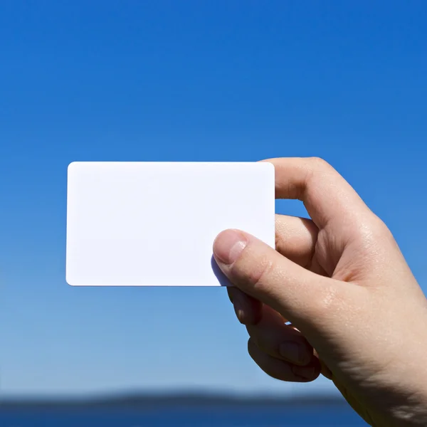 Hand presents white card on blue — Stock Photo, Image